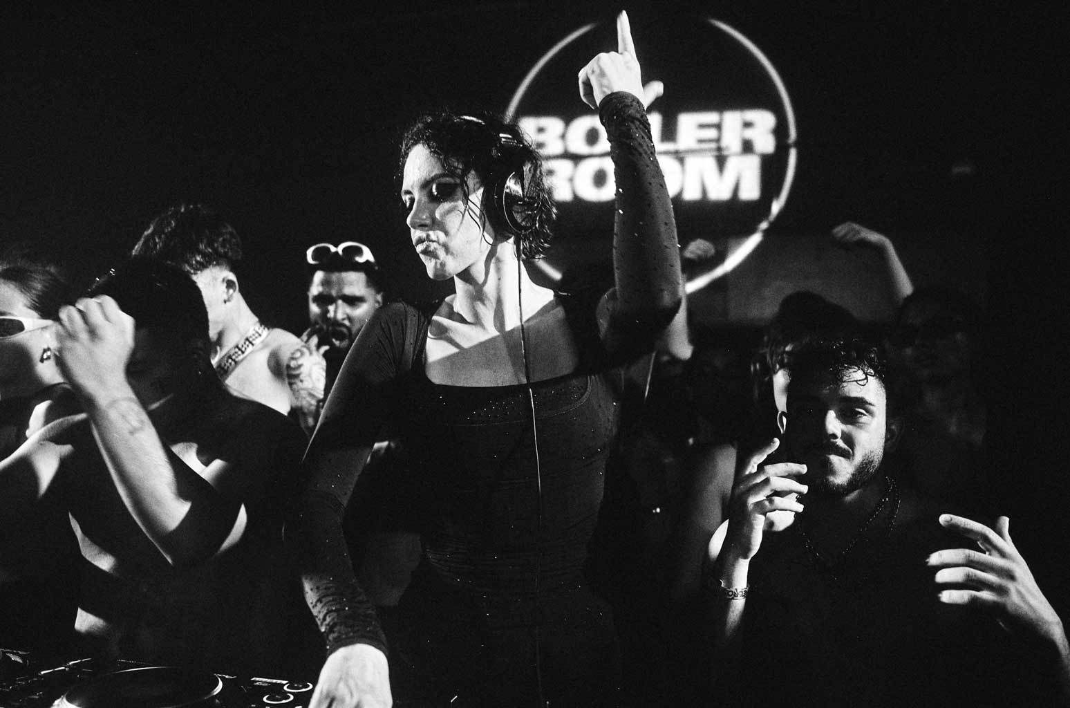 Sara Landry plays a Boiler Room set at Teletech Festival in 2023, one arm raised, the crowd around the decks and the Boiler Room logo behind her.